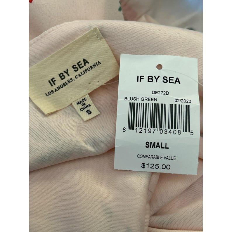 May include: A white tag with black text that reads "IF BY SEA" and "DE272D" with the words "BLUSH GREEN" and "02/2020" below. A barcode is below the text. The tag also says "SMALL" and "COMPARABLE VALUE $125.00".