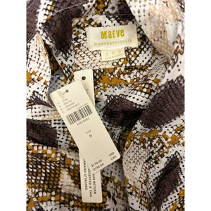 May include: A white and brown patterned shirt with a snake skin design. The shirt has a tag that says "Maeve by Anthropologie" and a size tag that says "6".
