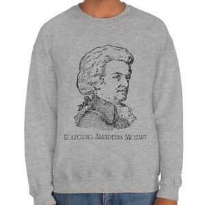 May include: A gray sweatshirt with a black and white illustration of Wolfgang Amadeus Mozart. The text "WOLFGANG AMADEUS MOZART" is printed below the illustration.