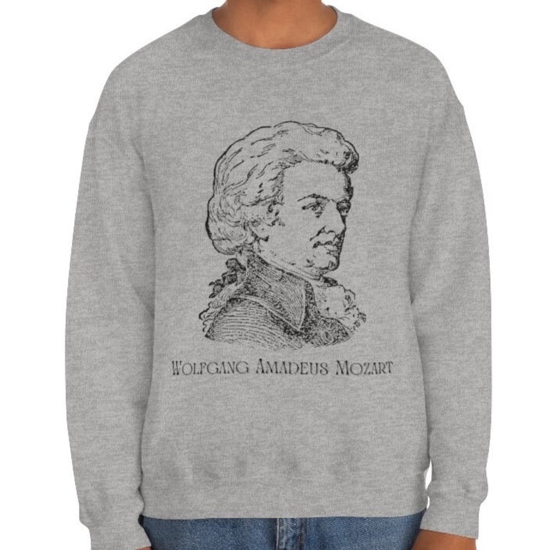 May include: A gray sweatshirt with a black and white illustration of Wolfgang Amadeus Mozart. The text "WOLFGANG AMADEUS MOZART" is printed below the illustration.