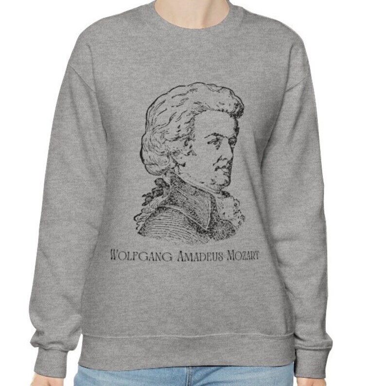 May include: A gray sweatshirt with a black and white illustration of Wolfgang Amadeus Mozart. The text "Wolfgang Amadeus Mozart" is printed below the illustration.