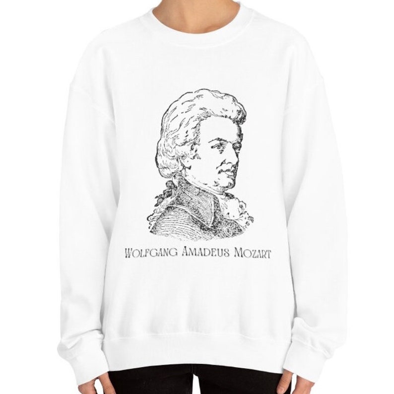 May include: White sweatshirt with a black and white illustration of Wolfgang Amadeus Mozart. The text "WOLFGANG AMADEUS MOZART" is printed below the illustration.