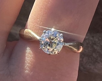 May include: A gold band ring with a large, clear, round diamond.