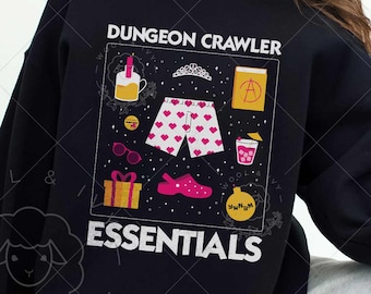 May include: Black sweatshirt with the text "DUNGEON CRAWLER ESSENTIALS" and a graphic of various items. The graphic includes a crown, shorts with hearts, sunglasses, a gift, a shoe, and a drink. The sweatshirt is worn by a person.