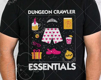 May include: Black t-shirt with the words "DUNGEON CRAWLER ESSENTIALS" and a graphic of various items, including a tiara, shorts with hearts, a gift, and a shoe. The shirt is worn by a person.