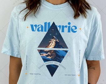 May include: Light blue t-shirt with a graphic of a mountain range and the text "valkyrie" in blue. The graphic is in a diamond shape with the text "NIGHT HIKE MT. RAINIER" at the bottom.