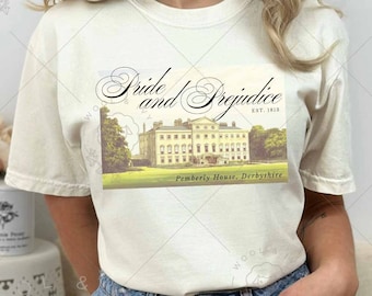 May include: A white t-shirt with a vintage postcard design featuring the text "Pride and Prejudice" and an image of Pemberley House, Derbyshire. The shirt is being modeled by a person wearing denim shorts.