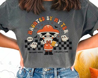 May include: Dark gray t-shirt with the text "HAUNTED BY MY TBR" and a cartoon mushroom character holding a book. The design includes ghosts and the phrases "TOO MANY BOOKS" and "TOO LITTLE TIME".