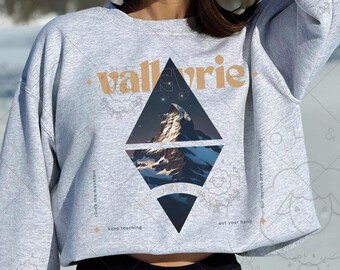May include: A gray sweatshirt with a mountain scene graphic and the text "val Avrie" in a diamond shape. The text "Keep Tracking" and "out your hand" are also visible on the sweatshirt.