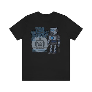 May include: Black t-shirt with a blue and gray graphic of a robot with the text "The Atomic Robot" and "Super-Plastic" printed on it.