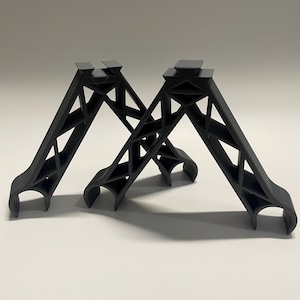 May include: Two black plastic shelf supports with a geometric design. The supports are angled and have a curved base.