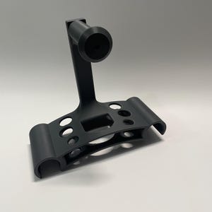 May include: A black plastic stand with multiple holes and a round handle. The stand is designed to hold and organise small items.