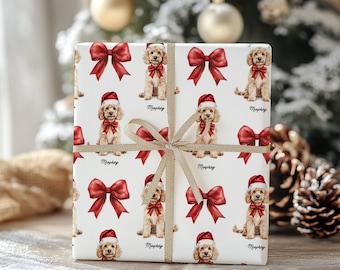 May include: A wrapped gift with a white background featuring a repeating pattern of a dog wearing a Santa hat and a red bow. The gift is tied with a gold ribbon and bow. The dog's name, "Murphy", is written below each dog.
