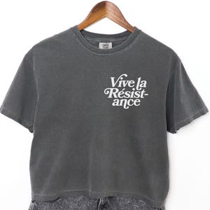 May include: A charcoal gray cropped t-shirt with a white graphic that reads "Vive la Résistance".