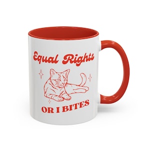 May include: White ceramic mug with a red interior and handle. The mug features a red illustration of a cat with the text "Equal Rights or I Bites" in red.