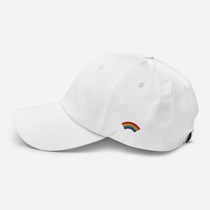May include: White baseball cap with a rainbow embroidered on the front.