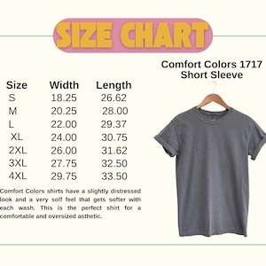 May include: A gray Comfort Colors short sleeve t-shirt displayed on a wooden hanger. The image includes a size chart with measurements in inches, ranging from S to 4XL. The text "SIZE CHART" is at the top.