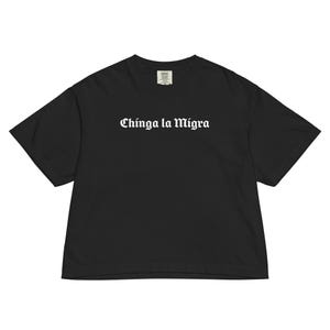 Pode incluir: T-shirt preto com a frase "Chinga la Migra" em letras g&oacute;ticas brancas. A camisa tem um corte folgado e mangas curtas. A pe&ccedil;a de roupa &eacute; feita de um material macio.