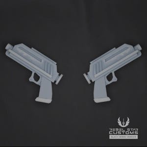 May include: Two light grey toy pistols are shown against a dark grey background. The pistols are replicas with detailed designs. The image includes the text "REBEL STAR CUSTOMS BLACK SERIES VENDOR".