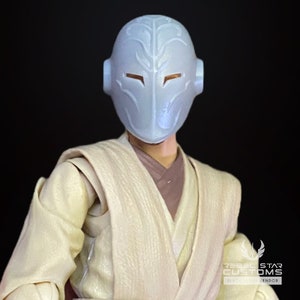Op de afbeelding: Een wit plastic actifiguur hoofd met een gedetailleerd gezichtsmasker. Het masker heeft een zilveren metallic afwerking en een ontwerp dat lijkt op een schedel. De figuur draagt een lichtbruine en witte robe.