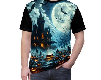 May include: A short-sleeve t-shirt featuring a graphic print of a haunted mansion under a large full moon. The scene includes flying bats, bare trees, and a field of glowing orange jack-o'-lanterns. The sleeves and collar are solid black.