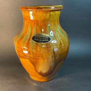 May include: A brown and green glazed ceramic vase with a label that reads "Dryden Potter's Wheel Original".