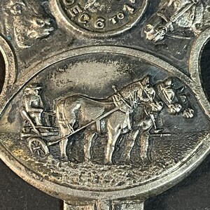 Puede incluir: Primer plano de una medalla de metal plateado con im&aacute;genes en relieve. El dise&ntilde;o central presenta un carruaje tirado por caballos con un conductor. La parte superior tiene el a&ntilde;o "1918" y las palabras "Dec 6 to 14". La medalla tiene una est&eacute;tica vintage detallada.
