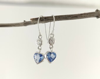 May include: A pair of silver dangle earrings with blue heart-shaped stones and clear crystal accents.