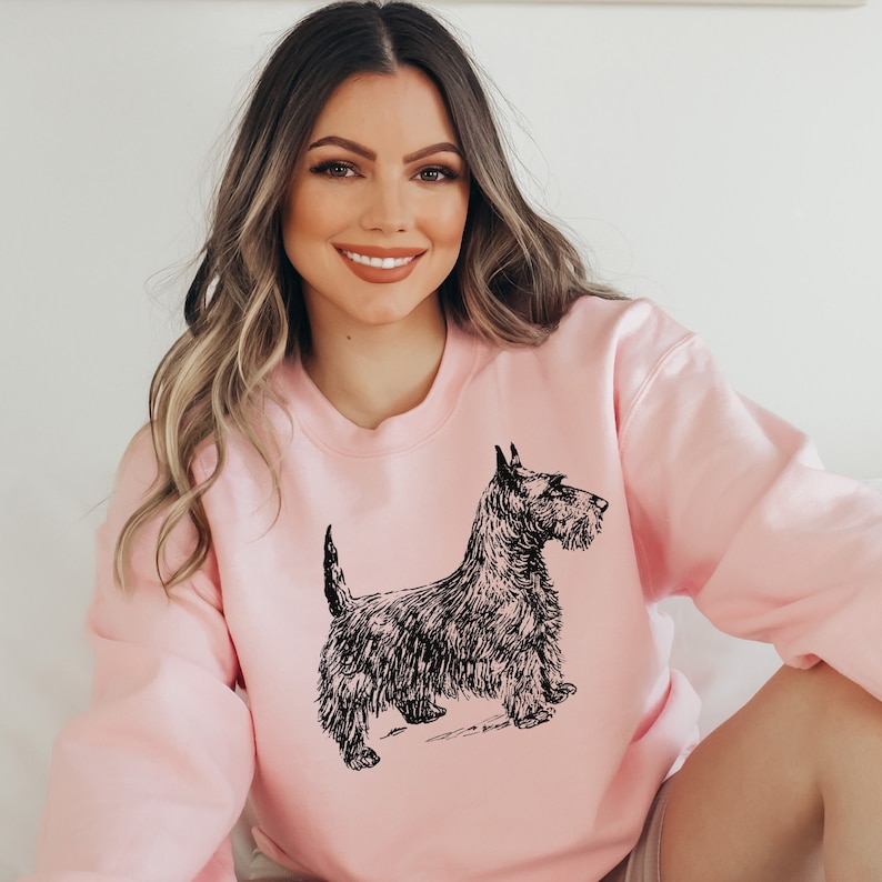 May include: A pink sweatshirt with a black and white illustration of a Scottish Terrier dog.