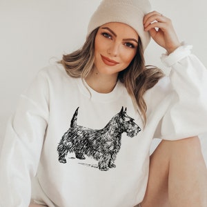 May include: A white sweatshirt with a black and white illustration of a Scottish Terrier dog.