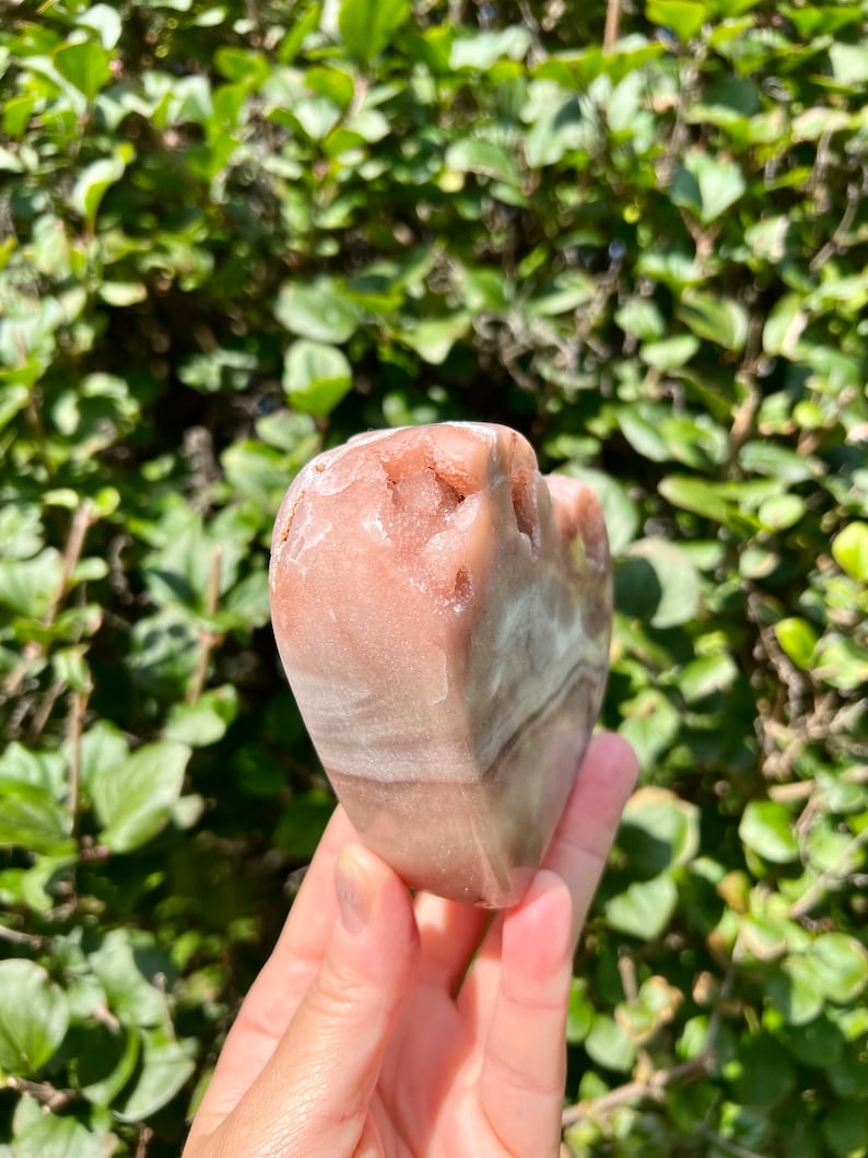 May include: A heart-shaped pink and white banded agate crystal. The crystal has a rough, natural texture.