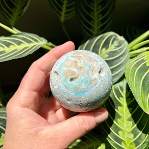 May include: A blue and white agate sphere with a swirling pattern. The sphere is smooth and polished.