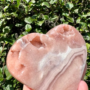 May include: A heart-shaped pink and white agate crystal with natural druzy and agate banding. The crystal is polished and has a smooth, glossy finish.