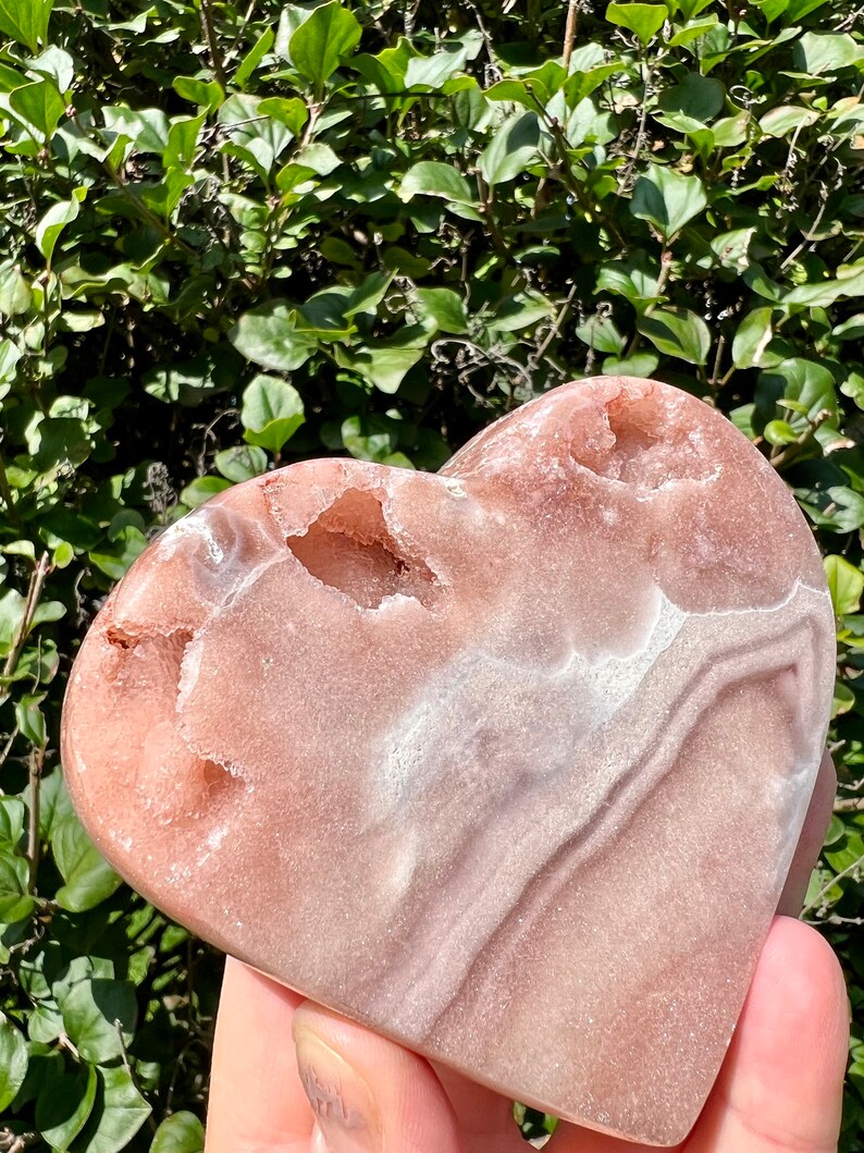 May include: A heart-shaped pink and white agate crystal with natural druzy and agate banding. The crystal is polished and has a smooth, glossy finish.