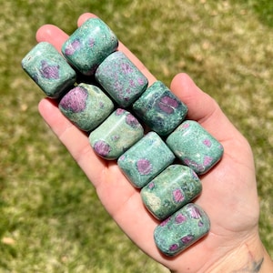 May include: A collection of ten tumbled green and pink ruby zoisite stones. The stones are smooth and polished, with a variety of shapes and sizes.