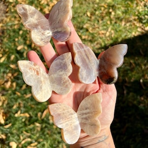 Peut inclure: Quatre sculptures de cristal de pierre de soleil en forme de papillon, de couleur blanche et brune irisée.