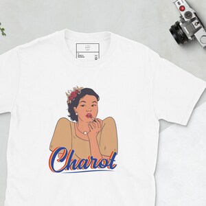 May include: White t-shirt with a retro illustration of a woman wearing a flower crown and a beige dress. The text "Charot" is printed in blue and orange below the illustration.