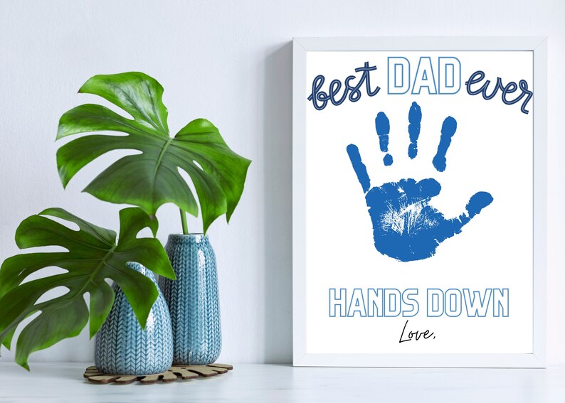 May include: A white framed print with a blue handprint and the text "best DAD ever HANDS DOWN Love."