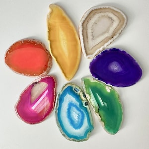 May include: Seven agate slices in various colors, including orange, yellow, white, purple, pink, blue, and green. The slices are arranged in a flower shape.