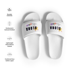 K&ouml;nnte beinhalten: Wei&szlig;e Riemchensandalen mit einem Regenbogen-Motiv "Aloha Vibes" und einem gelben Blumendesign.