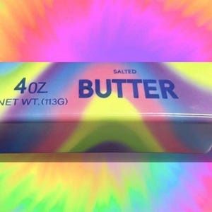 Op de afbeelding: Een blok gezouten boter van 113g met een regenboogontwerp. Het woord "BUTTER" staat in donkerblauw, met het gewicht en het woord "SALTED" erboven. De verpakking heeft een levendig, psychedelisch kleurenschema.