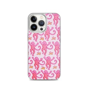 May include: A clear phone case featuring a repeating pattern of pink monkeys and yellow floral accents on a light pink background. The phone case has a clear border and a camera cutout.