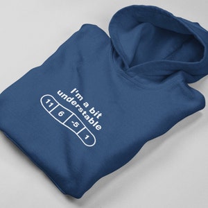 May include: A dark blue hoodie with a white graphic that says "I'm a bit understandable" and a white illustration of a band-aid with numbers 11, 6, -5, and 1.