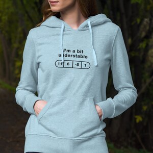 May include: A light blue hoodie with a white drawstring. The hoodie has a graphic print that says "I'm a bit understandable" with a pill shape underneath that has the numbers "11 6 -5 1" printed on it.