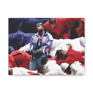 May include: A group of people wearing white, red, and blue clothing. A man in a blue and white jacket with the word "LO" on the front stands in the center of the image. The people are gathered around him, some are kneeling, some are standing, and some are lying down.