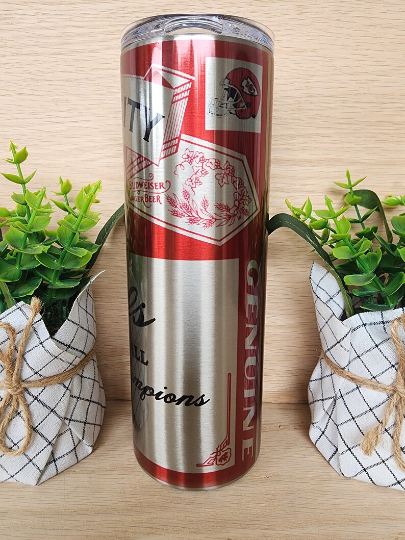 K&ouml;nnte beinhalten: Ein Edelstahlbecher mit einem rot-wei&szlig;-blauen Design. Der Becher zeigt einen Footballhelm und den Text "City" und "Genuine".