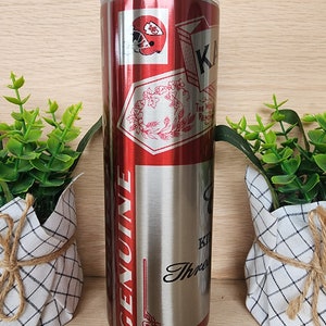 K&ouml;nnte beinhalten: Ein Edelstahlbecher mit einem roten und silbernen Design. Der Becher zeigt ein Logo der Kansas City Chiefs, ein Blumenmuster und die Worte "Genuine" und "The Most Rewarding."