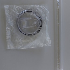 K&ouml;nnte beinhalten: Ein transparenter Plastikdeckel f&uuml;r eine Reise-Trinkflasche mit einem Schiebeverschluss. Der Deckel ist in einer transparenten Plastikt&uuml;te verpackt. Ein transparenter Plastikstrohhalm ist in einer separaten transparenten Plastikt&uuml;te verpackt.
