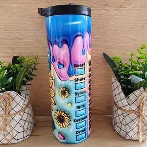 Puede incluir: Un vaso de acero inoxidable con un dise&ntilde;o colorido que presenta pintura goteando y girasoles. El vaso tiene una tapa y una pajita. El texto "Switch Coffee" est&aacute; impreso en el lateral del vaso.