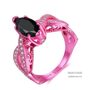 May include: A pink gold ring with a black marquise-shaped gemstone and small clear stones. The ring has a delicate, intricate design and is marked "18K GP".